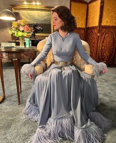 a woman sitting in a chair wearing a gray dress