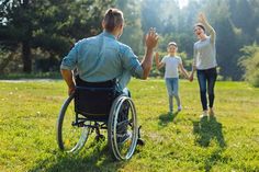 a man in a wheel chair with his hands up to the sky and two women walking behind him