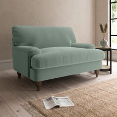 a blue couch sitting on top of a wooden floor next to a rug and window