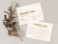 two thank cards sitting on top of each other next to a plant with leaves in it