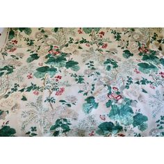 a white and green floral print bed spread with red flowers on the bottom half of it