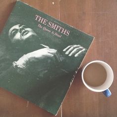 a book and cup sitting on top of a wooden table next to each other with the title, the smiths