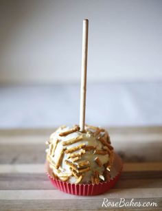 a cupcake covered in white frosting and sprinkles with a wooden stick sticking out of it