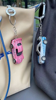 two purses with cars attached to them sitting next to each other