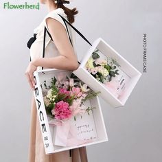 a woman holding two boxes with flowers in them