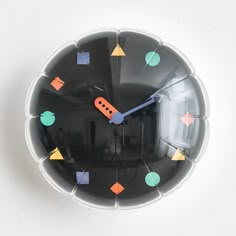 a black clock with colorful shapes on it's face and numbers in the middle