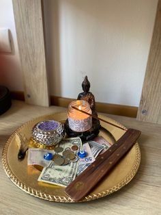 a tray with money, candles and other items on it sitting on a wooden table