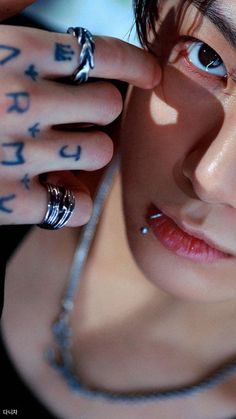 a woman with tattoos on her hands and fingers holding something in front of her face