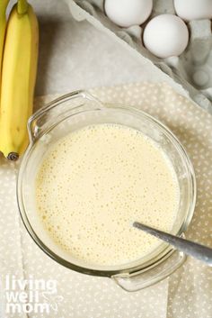 a glass bowl filled with white liquid next to some bananas