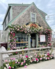 a building with flowers growing on the outside and inside it's front door, next to a wooden bench