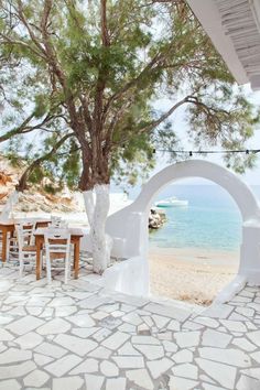 an outdoor dining area with tables and chairs on the beach next to the water's edge