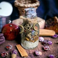 a glass bottle filled with lots of different things on top of a table next to other items