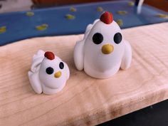 two plastic chickens sitting on top of a wooden table