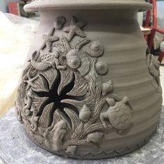 a clay pot with sea animals and shells on the outside, sitting on a table