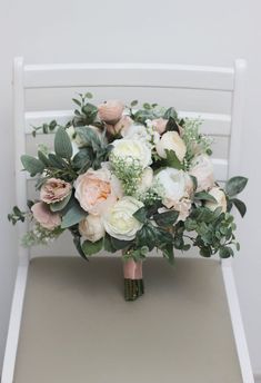 a bridal bouquet sitting on top of a white chair