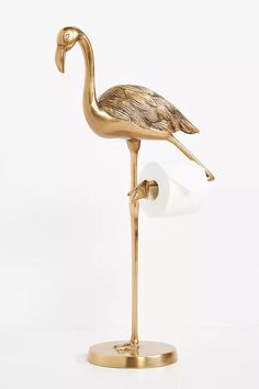 a gold flamingo standing on its hind legs with it's head turned to the side