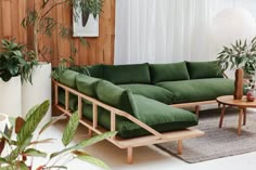 a living room with green couches and potted plants on the side table in front of it