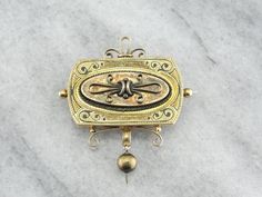 Absolutely stunning workmanship makes this Victorian era brooch all the more beautiful. The classical motif of the top is decorated with black enamel and wonderful texturing, and the textured bead dangle hangs perfectly. Ornate, gothic, and still sophisticated, this unique brooch would be a great piece to wear on just about any occasion! Love this piece but want to make it more versatile, we here at Market Square Jewelers along with our master metalsmiths can convert this fantastic brooch into a