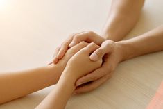 two people holding hands on top of a table