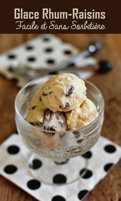 a glass bowl filled with ice cream on top of a wooden table next to polka dot napkin