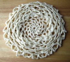 crocheted doily on a wooden surface with white yarn in the middle and center