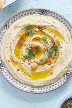 hummus with olives and parsley in a bowl on a blue tablecloth