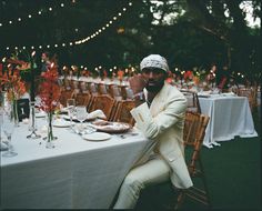 a man in a white suit sitting at a table