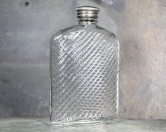 an empty glass bottle sitting on top of a stone counter next to a gray wall