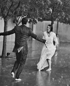 an old photo of two people dancing in the rain