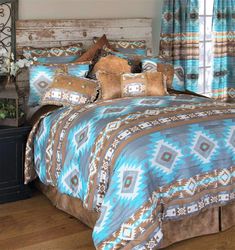 a bed with blue, brown and white comforter in a bedroom next to a window