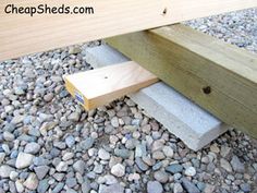 a wooden bench sitting on top of a gravel covered ground next to a pile of rocks