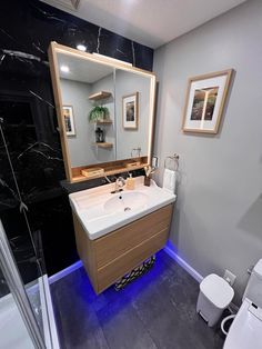 a bathroom with a sink, mirror and toilet in it's center area is lit up by blue lights