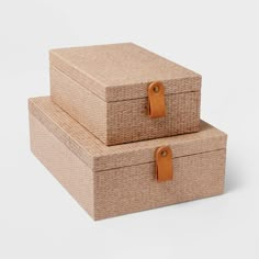 two woven boxes with leather handles are stacked on top of each other, one is empty