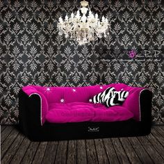 a black and pink couch sitting in front of a chandelier