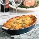 a casserole dish on a table with wine glasses