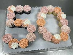 two cupcakes with pink and white frosting are arranged in the shape of the letter e