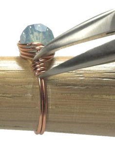 a ring with a faceted blue diamond sitting on top of a piece of wood