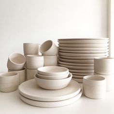 a stack of white plates and cups on a table