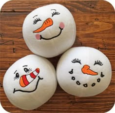 three balls with painted faces on them sitting on a wooden table next to each other