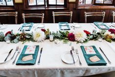 the table is set with silverware and flowers on it, along with place settings