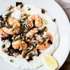 shrimp and mushrooms on top of rice with a lemon wedge next to it in a white bowl