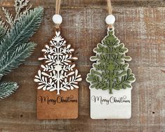 two wooden christmas ornaments hanging from twine on wood planks next to evergreen branches