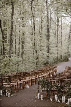 rows of wooden chairs set up in the woods for an outdoor ceremony with candles on them