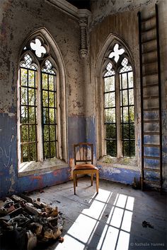 an old room with two windows and a chair