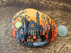 a painted rock sitting on top of a wooden table next to a dime coin holder