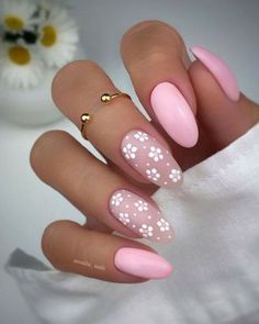 a manicure with pink and white flowers on the tip, gold ring around it