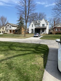 a car parked in front of a house on the side of a road next to grass