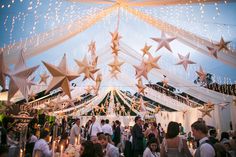 a large tent with many stars hanging from it's ceiling and people standing around