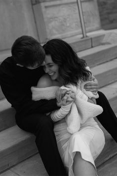 black and white photograph of a couple sitting on the steps together, hugging each other