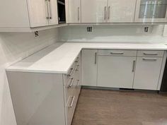 an empty kitchen with white cabinets and drawers